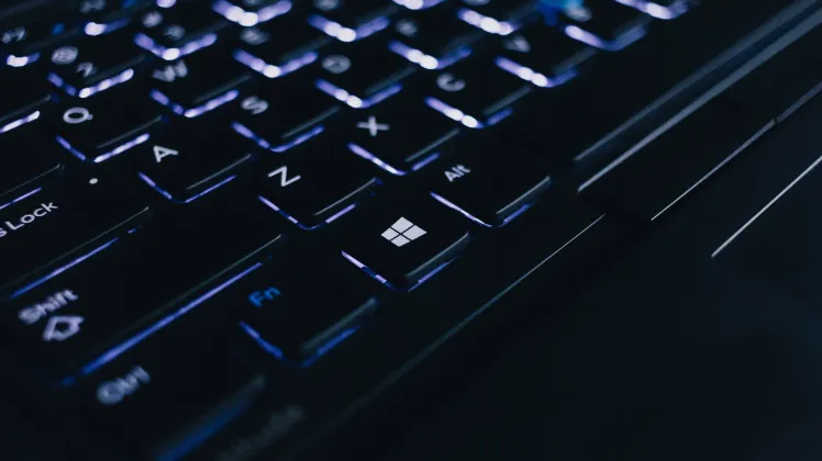 A close-up of a laptop keyboard and screen in a dark environment